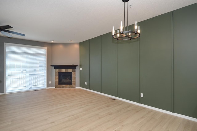 8397 Norwood Ln N, Maple Grove, MN 55311 - unfurnished living room featuring light wood-style flooring, a decorative wall, a chandelier, a tile fireplace, and a ceiling fan