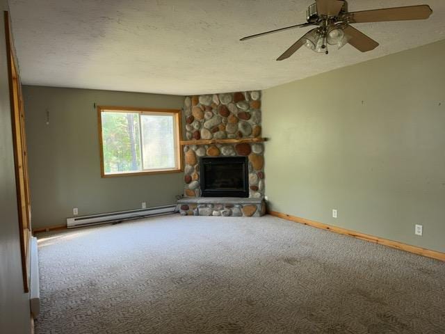 7300 County Road 8 NE, Longville, MN 56655 - unfurnished living room with baseboard heating, carpet flooring, a fireplace, ceiling fan, and a textured ceiling