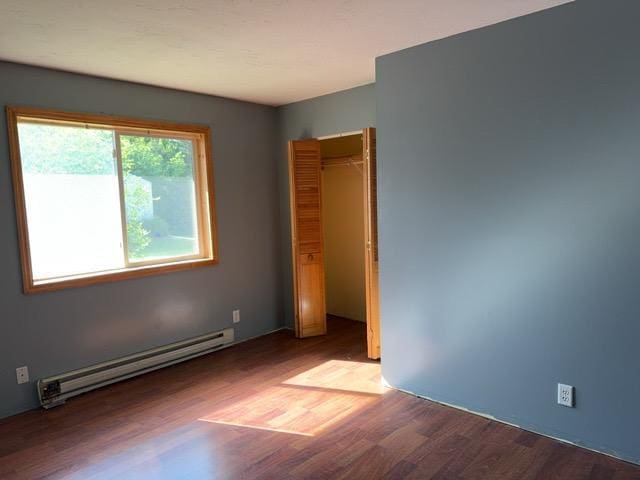 7300 County Road 8 NE, Longville, MN 56655 - unfurnished bedroom featuring a baseboard heating unit, wood finished floors, and a closet