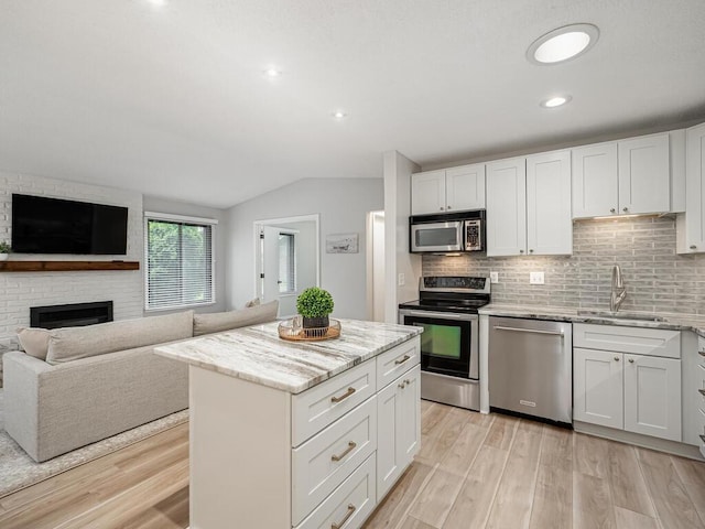 1181 Yuma Ln N, Plymouth, MN 55447 - kitchen with appliances with stainless steel finishes, light wood finished floors, light stone counters, vaulted ceiling, and decorative backsplash
