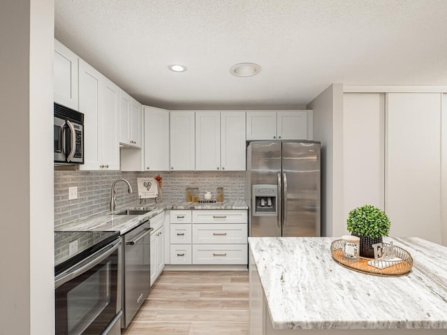 1181 Yuma Ln N, Plymouth, MN 55447 - kitchen with stainless steel appliances, light stone countertops, light wood-style flooring, decorative backsplash, and white cabinetry