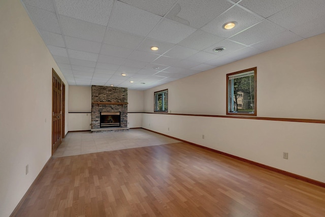 104 9th Ave N, Sartell, MN 56377 - unfurnished living room featuring light wood-type flooring, a brick fireplace, and a paneled ceiling