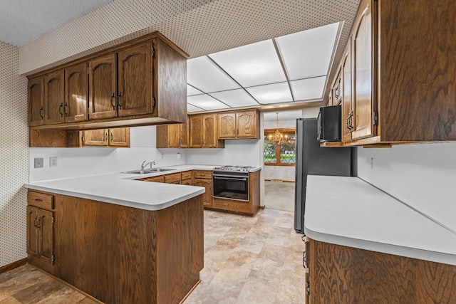 1267 Nursery Hill Ln, Arden Hills, MN 55112 - kitchen with wallpapered walls, range with gas stovetop, a peninsula, light countertops, and stone finish floors