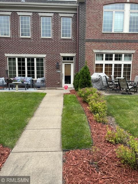 2460 119th Ct NE Unit D, Blaine, MN 55449 - back of house with an outdoor living space, brick siding, a patio, and a lawn