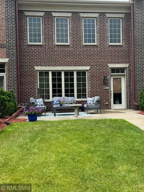 2460 119th Ct NE Unit D, Blaine, MN 55449 - rear view of property featuring an outdoor hangout area, brick siding, a patio area, and a lawn