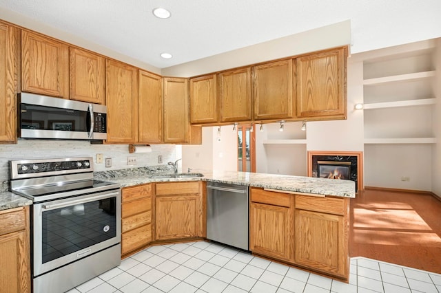 9035 Briarglen Rd, Eden Prairie, MN 55347 - kitchen with stainless steel appliances, a peninsula, decorative backsplash, light tile patterned floors, and a fireplace