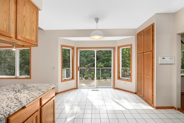 9035 Briarglen Rd, Eden Prairie, MN 55347 - kitchen with healthy amount of natural light, hanging light fixtures, light stone countertops, and light tile patterned floors