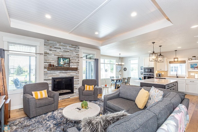 2865 Mcleod Dr E, West Fargo, ND 58078 - living area featuring light wood-type flooring, a raised ceiling, a chandelier, and recessed lighting