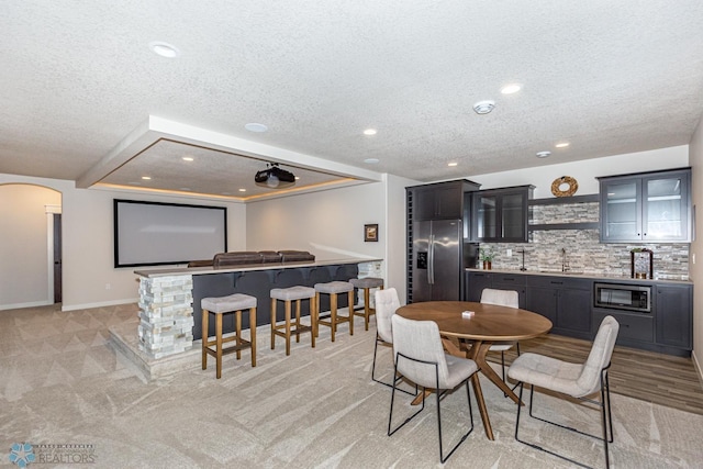 2865 Mcleod Dr E, West Fargo, ND 58078 - dining space with bar with sink, a textured ceiling, light colored carpet, arched walkways, and recessed lighting