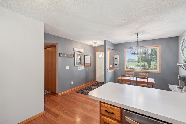 728 Elm St, Belle Plaine, MN 56011 - kitchen with a chandelier, light wood-type flooring, light countertops, a textured ceiling, and dishwashing machine