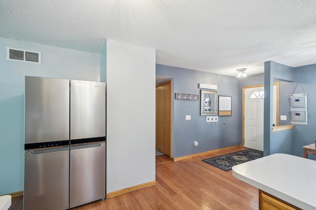 728 Elm St, Belle Plaine, MN 56011 - kitchen with freestanding refrigerator, a textured ceiling, and light wood finished floors