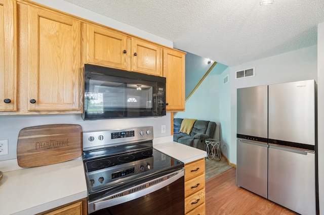 728 Elm St, Belle Plaine, MN 56011 - kitchen with stainless steel appliances, light countertops, light wood-style floors, and a textured ceiling