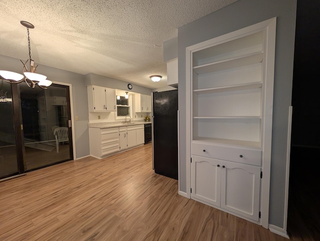 507 1st St, Marshall, MN 56258 - kitchen with freestanding refrigerator, a chandelier, a textured ceiling, light wood finished floors, and white cabinets