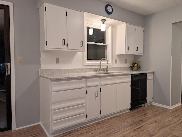 507 1st St, Marshall, MN 56258 - kitchen featuring black dishwasher, light wood-style flooring, white cabinets, light countertops, and a textured ceiling