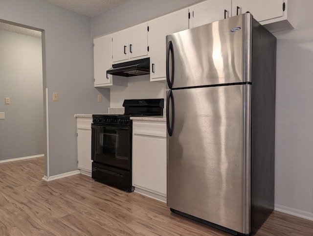 507 1st St, Marshall, MN 56258 - kitchen with freestanding refrigerator, gas stove, under cabinet range hood, light countertops, and light wood-type flooring
