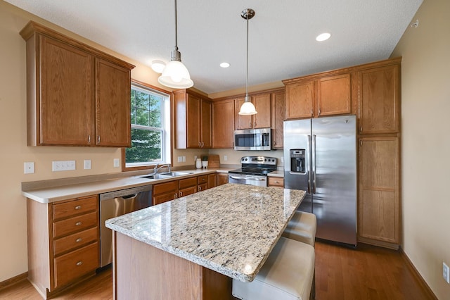 16618 72nd Ct NE, Otsego, MN 55330 - kitchen featuring appliances with stainless steel finishes, wood finished floors, brown cabinets, a kitchen island, and recessed lighting