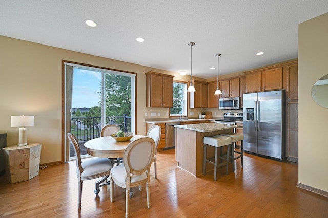 16618 72nd Ct NE, Otsego, MN 55330 - kitchen featuring appliances with stainless steel finishes, brown cabinets, a center island, light wood-type flooring, and light countertops