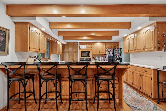 940 Brown Rd S, Wayzata, MN 55391 - kitchen with black appliances, light wood finished floors, beam ceiling, a peninsula, and a kitchen breakfast bar