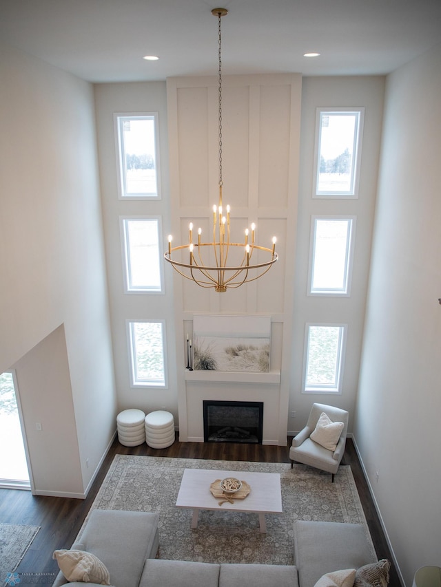 1449 66th Ave S, Fargo, ND 58104 - living room featuring dark wood-style flooring, healthy amount of natural light, a towering ceiling, a chandelier, and a fireplace