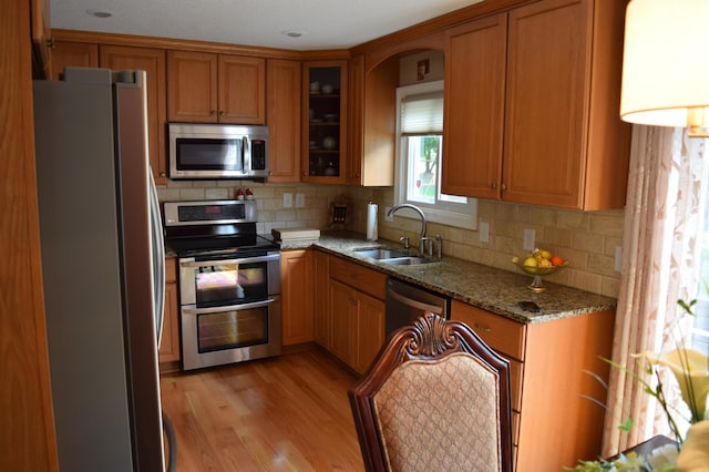 12115 50th Ave N, Plymouth, MN 55442 - kitchen featuring stainless steel appliances, brown cabinetry, light stone counters, light wood-style flooring, and backsplash