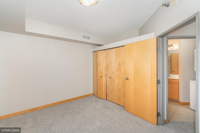 2600 University Ave SE Unit 318, Minneapolis, MN 55414 - unfurnished bedroom with light carpet, a closet, and a textured ceiling