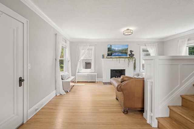 1407 Pascal St N, Saint Paul, MN 55108 - living area featuring radiator heating unit, light wood-style flooring, crown molding, a brick fireplace, and stairs