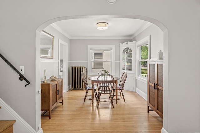 1407 Pascal St N, Saint Paul, MN 55108 - dining room featuring radiator heating unit, crown molding, light wood finished floors, stairs, and arched walkways