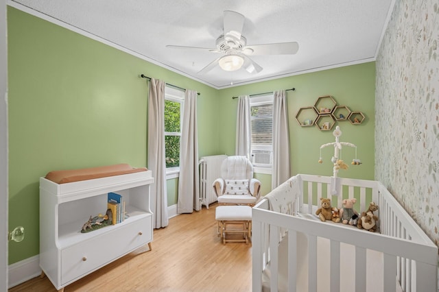 1407 Pascal St N, Saint Paul, MN 55108 - bedroom featuring radiator heating unit, wallpapered walls, a nursery area, wood finished floors, and crown molding