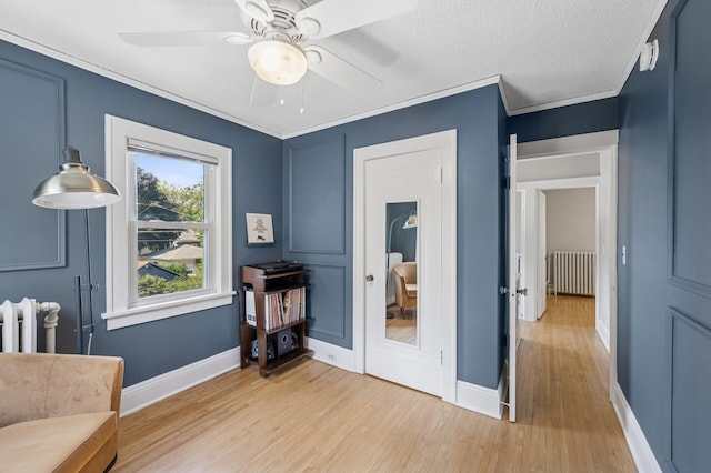 1407 Pascal St N, Saint Paul, MN 55108 - living area featuring radiator heating unit, light wood-style flooring, a ceiling fan, and ornamental molding