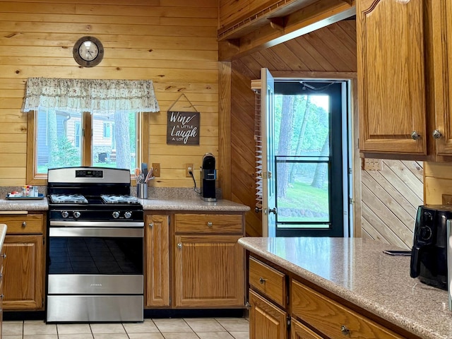 3025 Viewpoint Rd, Isle, MN 56342 - kitchen with stainless steel gas stove, wooden walls, light tile patterned flooring, light countertops, and brown cabinetry