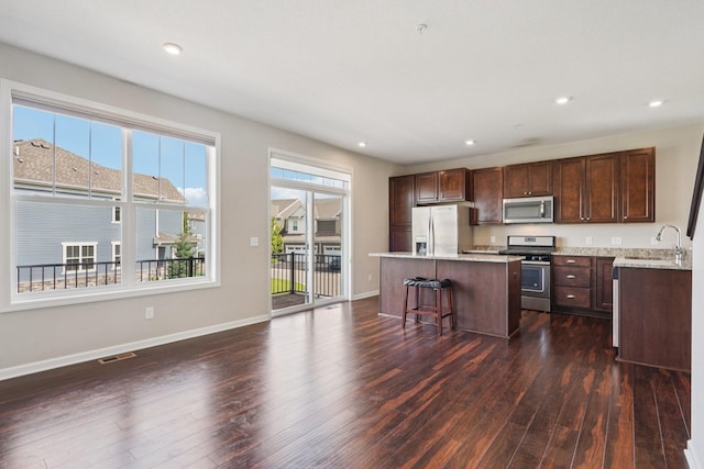 8169 Central Park Way N, Maple Grove, MN 55369 - kitchen with stainless steel appliances, a kitchen island, dark wood-style floors, recessed lighting, and dark brown cabinetry