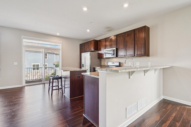 8169 Central Park Way N, Maple Grove, MN 55369 - kitchen featuring stainless steel appliances, a breakfast bar, dark wood-style flooring, recessed lighting, and dark brown cabinets