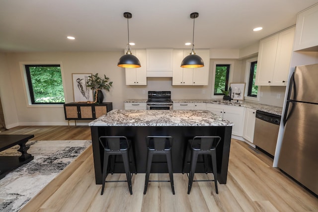 7719 Canary Rd SW, Alexandria, MN 56308 - kitchen with stainless steel appliances, light wood-style flooring, a kitchen island, white cabinetry, and a breakfast bar