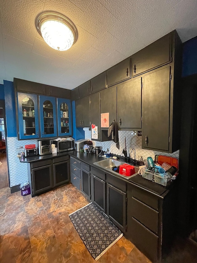 407 Minnesota St, Redwood Falls, MN 56283 - kitchen featuring stainless steel microwave, dark countertops, glass insert cabinets, and decorative backsplash
