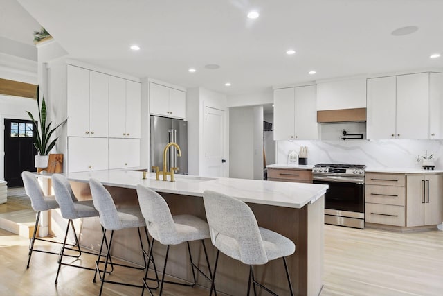 1611 Hill Ridge Ter, Minnetonka, MN 55305 - kitchen featuring appliances with stainless steel finishes, modern cabinets, light wood-type flooring, a kitchen bar, and recessed lighting