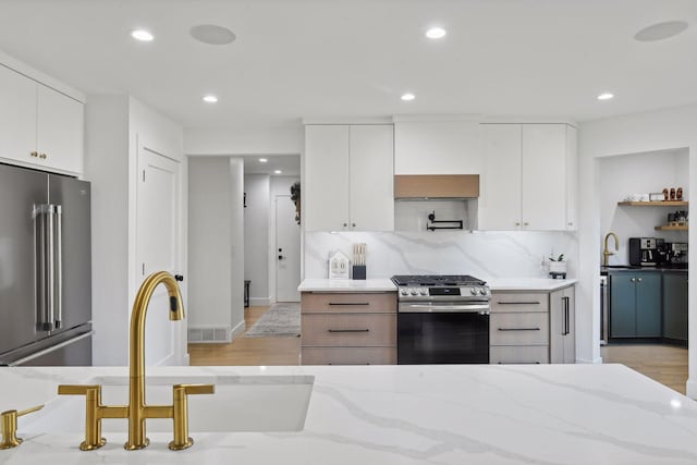 1611 Hill Ridge Ter, Minnetonka, MN 55305 - kitchen with stainless steel appliances, recessed lighting, white cabinetry, light stone countertops, and light wood-style floors