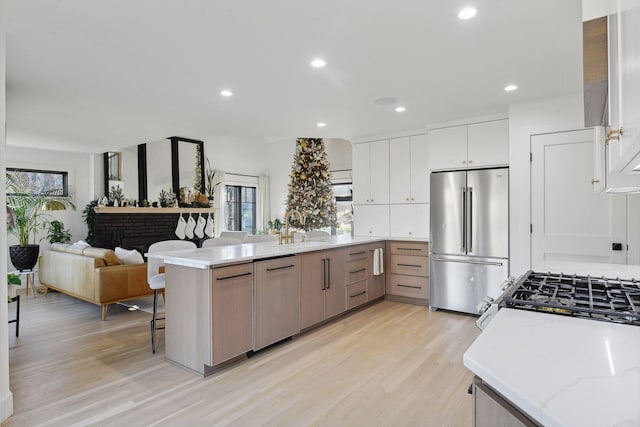 1611 Hill Ridge Ter, Minnetonka, MN 55305 - kitchen with appliances with stainless steel finishes, a peninsula, light wood-style flooring, open floor plan, and white cabinets