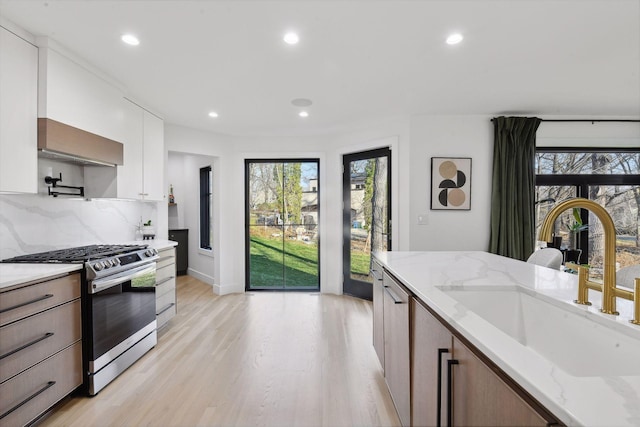 1611 Hill Ridge Ter, Minnetonka, MN 55305 - kitchen featuring stainless steel gas range oven, wall chimney range hood, light wood-type flooring, recessed lighting, and plenty of natural light