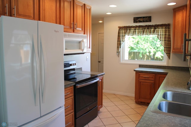 509 24th Ave N, Fargo, ND 58102 - kitchen featuring white appliances, brown cabinets, light tile patterned floors, recessed lighting, and dark countertops