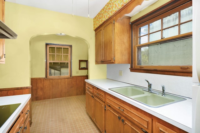 3609 Elliot Ave, Minneapolis, MN 55407 - kitchen featuring wainscoting, brown cabinetry, light countertops, wood walls, and range hood