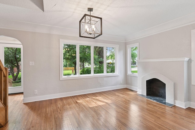 3305 Huntington Ave, Saint Louis Park, MN 55416 - unfurnished living room featuring plenty of natural light, wood finished floors, a chandelier, a fireplace, and a textured ceiling
