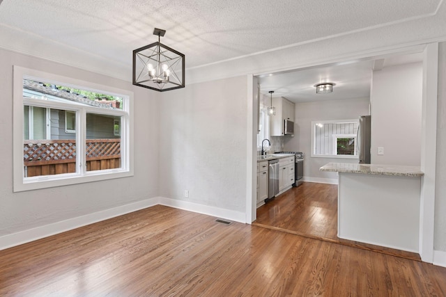 3305 Huntington Ave, Saint Louis Park, MN 55416 - kitchen with a chandelier, appliances with stainless steel finishes, wood finished floors, white cabinets, and hanging light fixtures