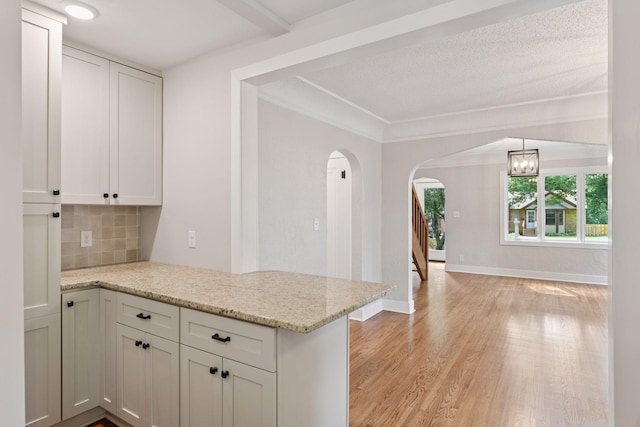 3305 Huntington Ave, Saint Louis Park, MN 55416 - kitchen featuring a peninsula, tasteful backsplash, arched walkways, light wood finished floors, and light stone countertops