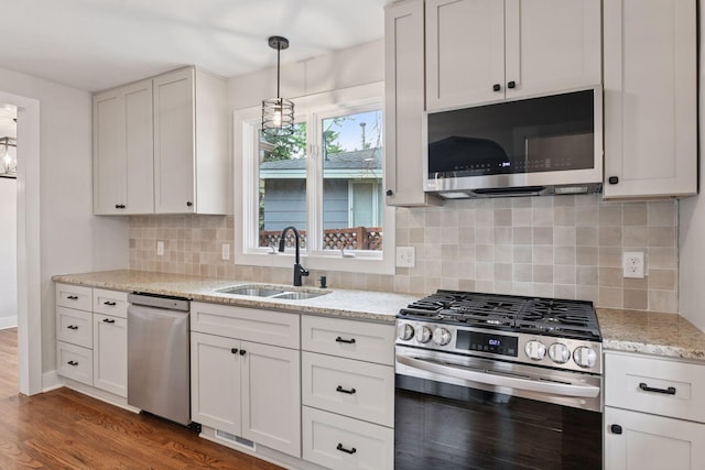 3305 Huntington Ave, Saint Louis Park, MN 55416 - kitchen featuring appliances with stainless steel finishes, dark wood-style flooring, light stone countertops, decorative light fixtures, and backsplash