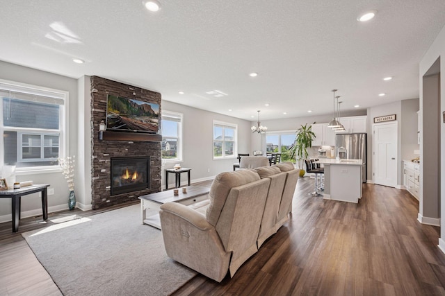 14660 109th Ave N, Maple Grove, MN 55369 - living room featuring dark wood finished floors, a fireplace, recessed lighting, a chandelier, and a textured ceiling