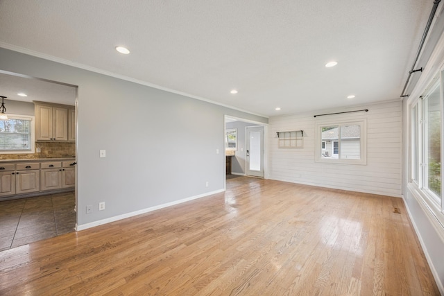 12209 Davenport St NE, Blaine, MN 55449 - unfurnished living room featuring light wood finished floors, plenty of natural light, crown molding, and recessed lighting