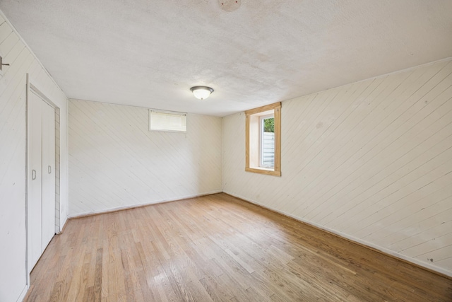 12209 Davenport St NE, Blaine, MN 55449 - unfurnished bedroom featuring hardwood / wood-style floors, wooden walls, and a textured ceiling