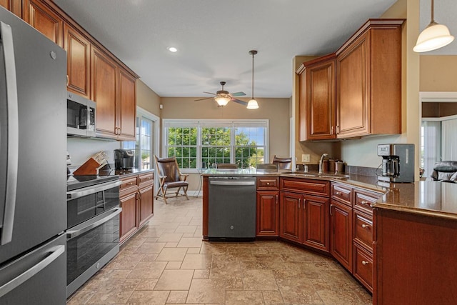 1904 Rock Ridge Ln, Saint Peter, MN 56082 - kitchen featuring appliances with stainless steel finishes, a peninsula, stone tile flooring, ceiling fan, and decorative light fixtures