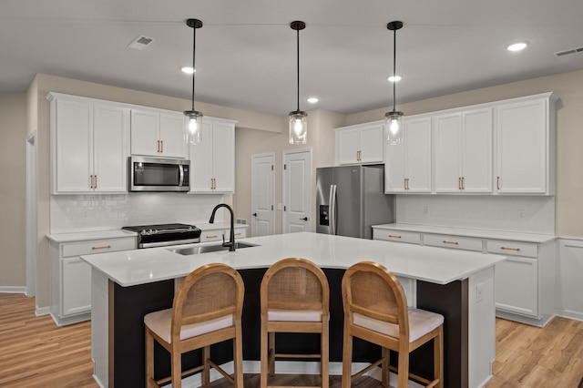 2570 Paddock Path, Shakopee, MN 55379 - kitchen with appliances with stainless steel finishes, a center island with sink, backsplash, light wood-type flooring, and light countertops