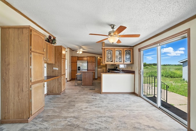 6257 State Highway 70, Rock Creek, MN 55063 - kitchen with a textured ceiling, ceiling fan, a kitchen island, stainless steel refrigerator with ice dispenser, and brown cabinetry